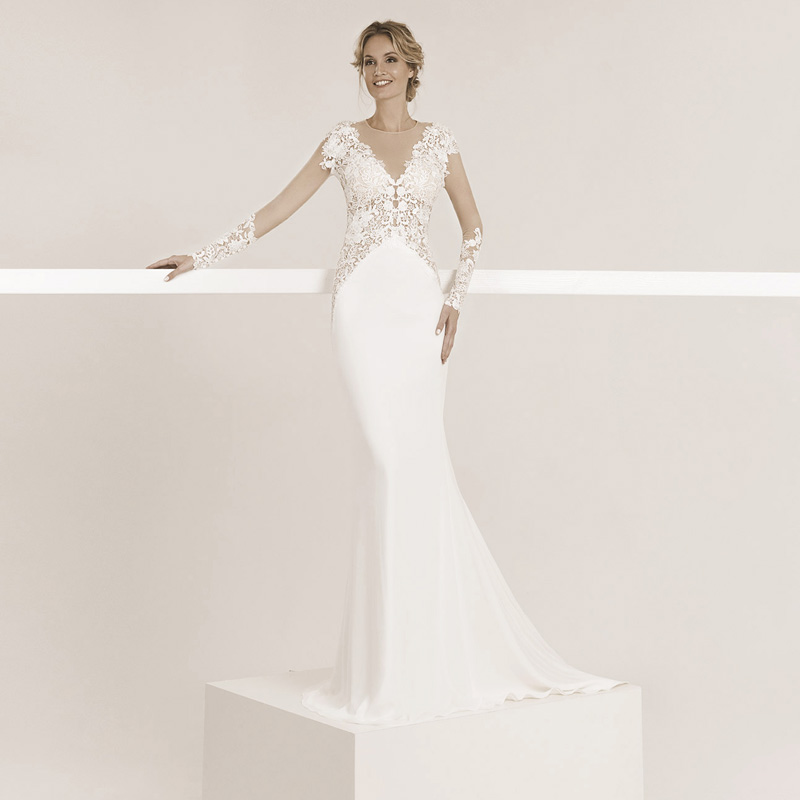 Model trägt ein eng anliegendes Hochzeitskleid mit Spitze, das Oberteil ist langarm der Rücken ganz offen